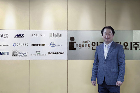 Ingang Audio CEO, Steve Kim, in front of the company’s logo wall